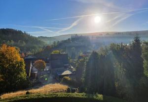 a village in a valley with the sun in the sky at Haus Nietmann_ Ferienwohnung 4 in Altenau +15 photos
