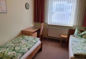 a room with two beds and a desk and a window at Haus Nietmann_ Ferienwohnung 4 in Altenau