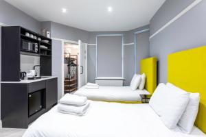 two beds in a room with blue and yellow at Kensington Rooms - Warwick Road in London