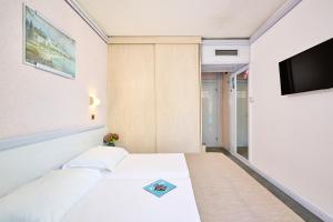 ein Hotelzimmer mit einem Bett und einem Flachbild-TV in der Unterkunft Hotel Plavi Plava Laguna in Poreč