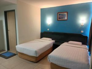 two beds in a hotel room with blue walls at Monaco Hotel in Tawau
