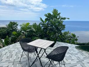 een tafel en 2 stoelen op een patio met uitzicht op de oceaan bij la maison du nord in Acoua +2 foto's