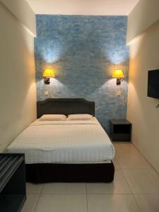 um quarto com uma cama e uma parede azul em Monaco Hotel em Tawau