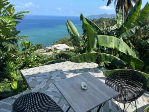 a wooden table and chairs with the ocean in the background at la maison du nord in Acoua