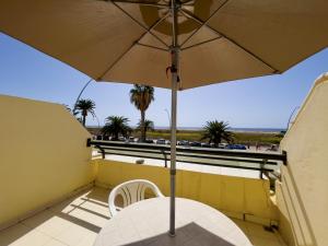 a table and chair under an umbrella on a balcony at Matorral Beach Apartament beautiful ocean view in Morro del Jable