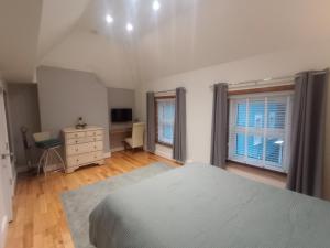 a bedroom with a bed and a dresser and two windows at Folkestone harbour view in Folkestone