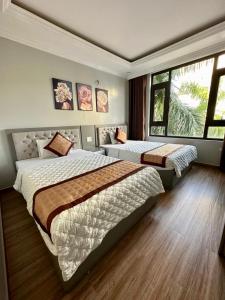 a bedroom with two beds and a large window at Việt Hoàng Hotel Hạ Long in Ha Long