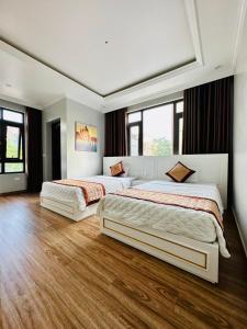 - 2 lits dans une chambre dotée de parquet et de fenêtres dans l'établissement Việt Hoàng Hotel Hạ Long, à Hạ Long