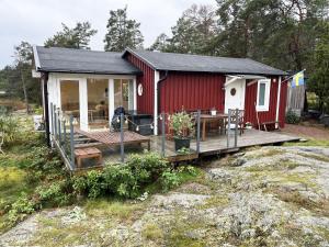 een rood huisje met een terras en een tafel bij Nice cottage located on a seaside plot outside Oskarshamn in Oskarshamn