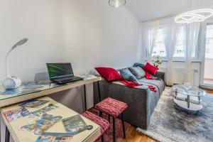 Apartment Saga With Terrace And Parking - Happy Rentals في زغرب: غرفة معيشة مع أريكة وجهاز كمبيوتر محمول على طاولة