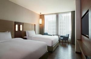 ソウルにあるコートヤード バイ マリオット ソウル 南大門のベッド2台、テーブル、テレビが備わるホテルルームです。