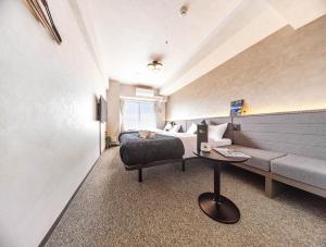 a bedroom with a bed and a couch and a table at Apartment Hotel 11 Shinsaibashi II in Osaka