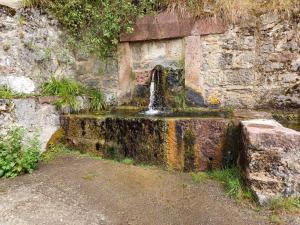 una fuente de agua en una pared de piedra en Casa G. Mirador de las Ubiñas, en Ríospaso