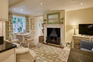 Guinea Cottage في Great Somerford: غرفة معيشة مع موقد وغرفة معيشة مع تلفزيون