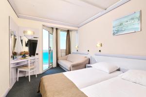 ein Hotelzimmer mit zwei Betten und einem Schreibtisch in der Unterkunft Hotel Plavi Plava Laguna in Poreč