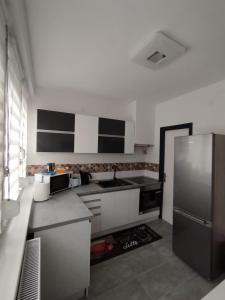 a kitchen with white cabinets and a stainless steel refrigerator at Cosmopolitan Apartman in Sárospatak
