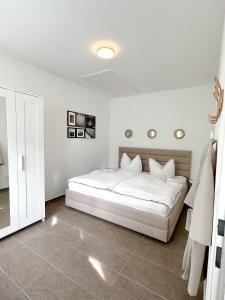 a white bedroom with a bed with white sheets at Modernes Haus nähe Parndorf in Bruck an der Leitha