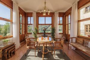 comedor con mesa, sillas y ventanas en Masia Can Orta, en Sant Feliu de Buixalleu