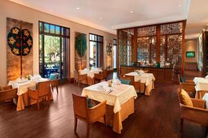 un restaurante con mesas y sillas blancas y ventanas en The St. Regis Lhasa Resort, en Lhasa