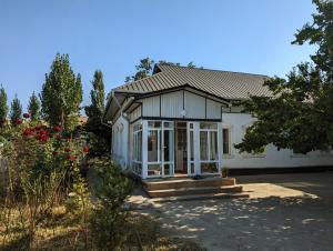 uma pequena casa branca com um alpendre e flores em Rice House Near Uzgen 
