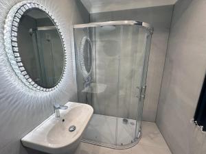 a bathroom with a shower and a sink and a mirror at Modernised 4 Bedroom House close to city Centre, Kep Stays in Leeds