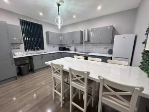 a kitchen with a white counter and a table and chairs at Modernised 4 Bedroom House close to city Centre, Kep Stays in Leeds