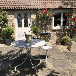 Guinea Cottage في Great Somerford: طاولة و كرسيين امام المنزل