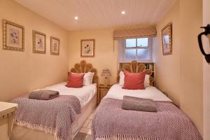 two twin beds in a room with a window at Guinea Cottage in Great Somerford