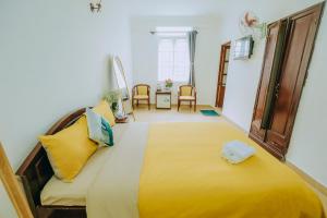 a bedroom with a large bed with yellow pillows at Wealth Pearl Dalat Hotel in Da Lat