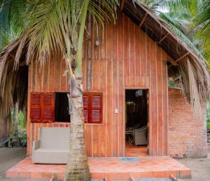 a house with a palm tree in front of it at HƯNG THÀNH HOME in Ben Tre