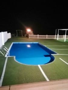 洛哈的住宿－4 bedrooms villa with private pool and furnished terrace at Loja，享有网球场和游泳池的夜景