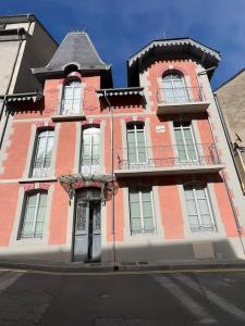 a tall red and white building with windows at Joli T3 rénové ds une villa 1900 in Cauterets