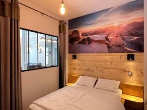 a bedroom with a bed with a painting on the wall at Joli T3 rénové ds une villa 1900 in Cauterets