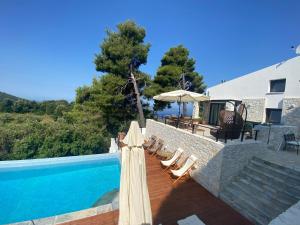 uma piscina com espreguiçadeiras e um guarda-sol ao lado de uma casa em Allure Luxury Villas em Skiathos