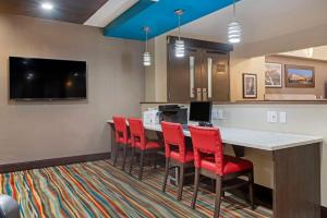 a room with a bar with red chairs and a tv at Best Western PLUS Port O'Call Hotel in Calgary