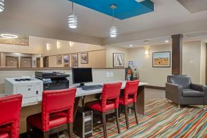 a lobby with a desk with a computer and red chairs at Best Western PLUS Port O'Call Hotel in Calgary