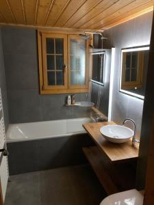 La salle de bains est pourvue d'une baignoire, d'un lavabo et de toilettes. dans l'établissement Chalet Soldanella 10 guests Gstaad, à Gstaad
