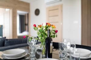 a table with a bottle of wine and a vase of flowers at EASY RENT Apartments - Kompozytorów Old Town View in Lublin