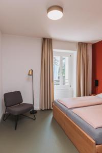 um quarto com uma cama, uma cadeira e uma janela em Montreux Youth Hostel em Montreux
