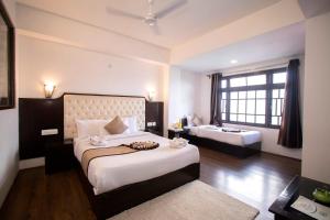 a bedroom with two beds and a large window at Tiara Regency Gangtok in Gangtok