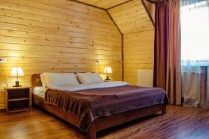 sypialnia z łóżkiem w drewnianej ścianie w obiekcie Готель Поляницький w mieście Bukowel