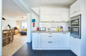 eine Küche mit weißen Schränken und ein Wohnzimmer in der Unterkunft Sunny Days: Beautiful Spacious 4 bed house in Torquay