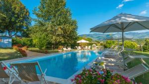a swimming pool with chairs and an umbrella at VILLA LEONARDO 30&6 Emma Villas in Burchio