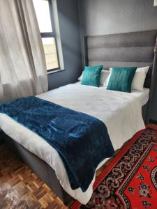 a bedroom with a large bed with a blue blanket on it at Ezcel accommodation in Cape Town