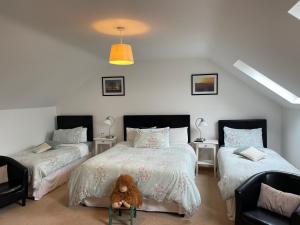 a bedroom with two beds and a teddy bear sitting on a chair at Corrib View Lodge in Glencorrib