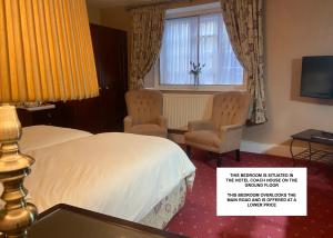 a hotel room with a bed and two chairs and a window at Stow Lodge Hotel in Stow on the Wold
