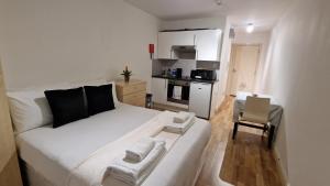 a white bed in a small room with a kitchen at Compact living cosy studio flat in london in London