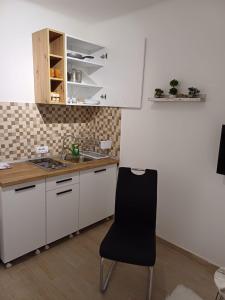 a kitchen with white cabinets and a black chair at BelDor Apartment in Belgrade