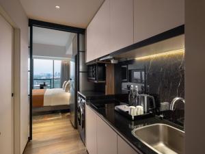 a kitchen with a sink and a bed in a room at Herloom Hotel & Residence BSD Tangerang in Tangerang