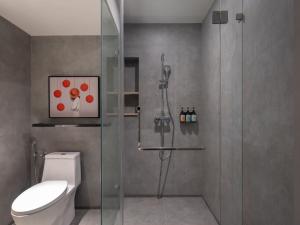 a bathroom with a shower stall and a toilet at Herloom Hotel & Residence BSD Tangerang in Tangerang